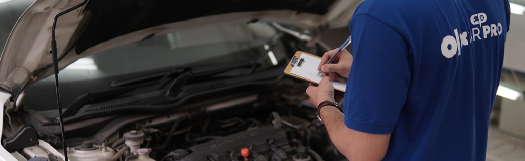 A carpro inspector is carrying out a car inspection of a car on the cars engine.