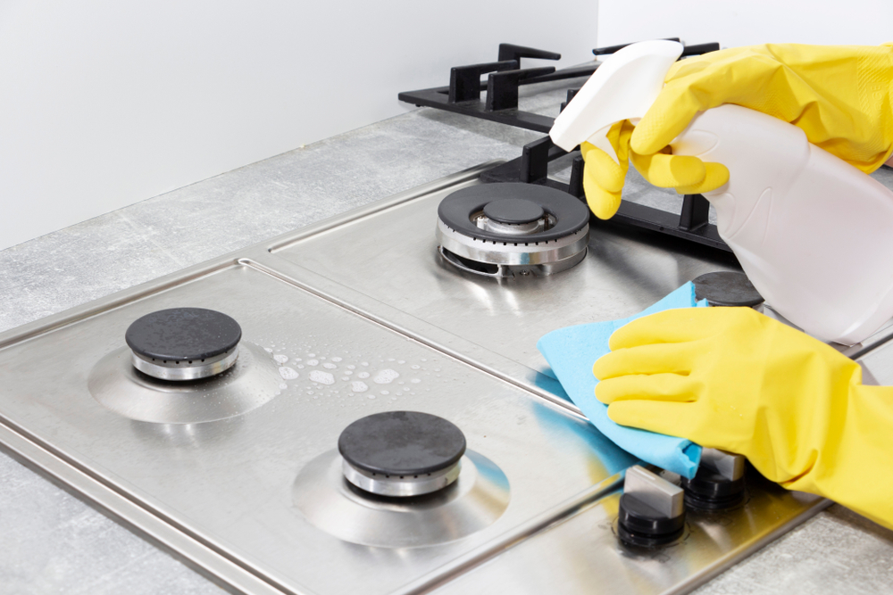 cleaning-stove-with-yellow-gloves-on